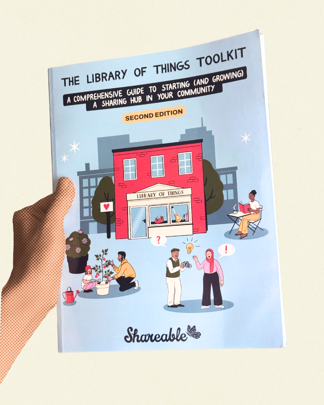 a picture of a hand holding a physical copy of the library of things toolkit